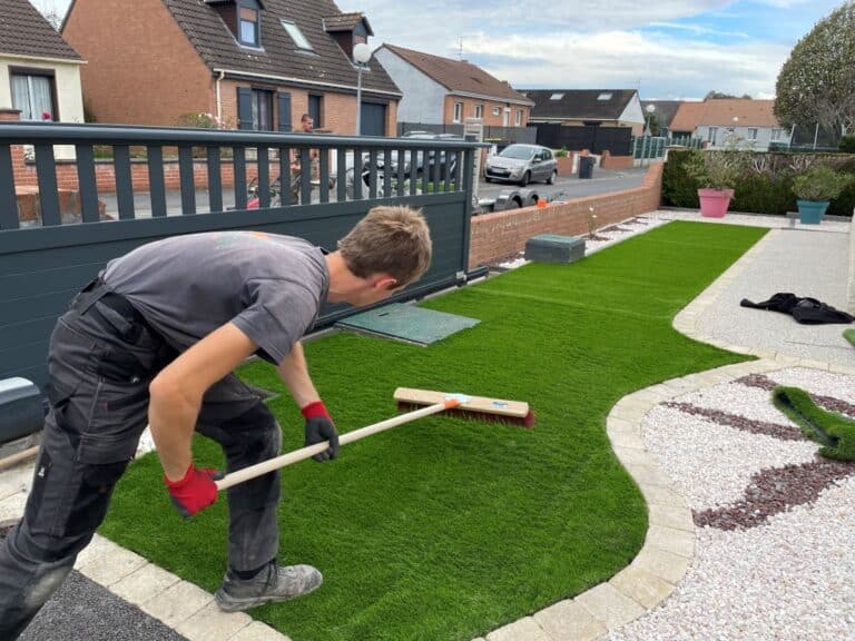 artisan qui pose du gazon synthetique dans une cour de maison